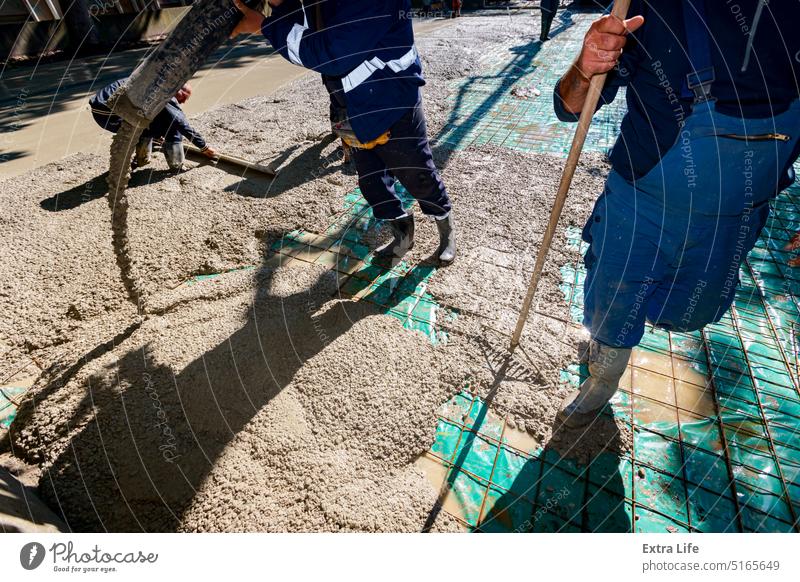 Rigger, Arbeiter hält den Pumpenschlauch, um frischen Beton in das Gebäudefundament über Bewehrungsstangen zu gießen beitreten Ausrichten Armatur Basis Stiefel