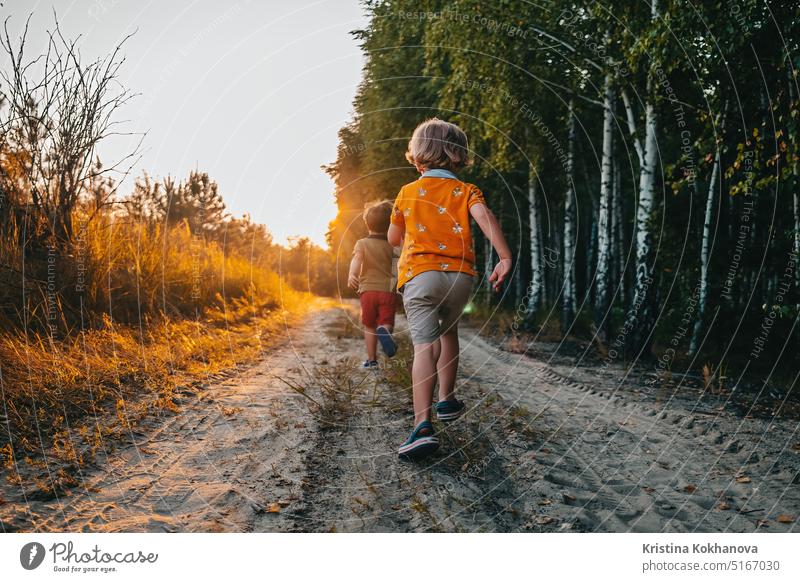 Niedliche Kinder, Jungen läuft im Sommer Natur Straße. Brüder, spielen im Freien. Sonnenuntergang. aktiver Lebensstil Bruder Kinderunterhaltung Stadtpark