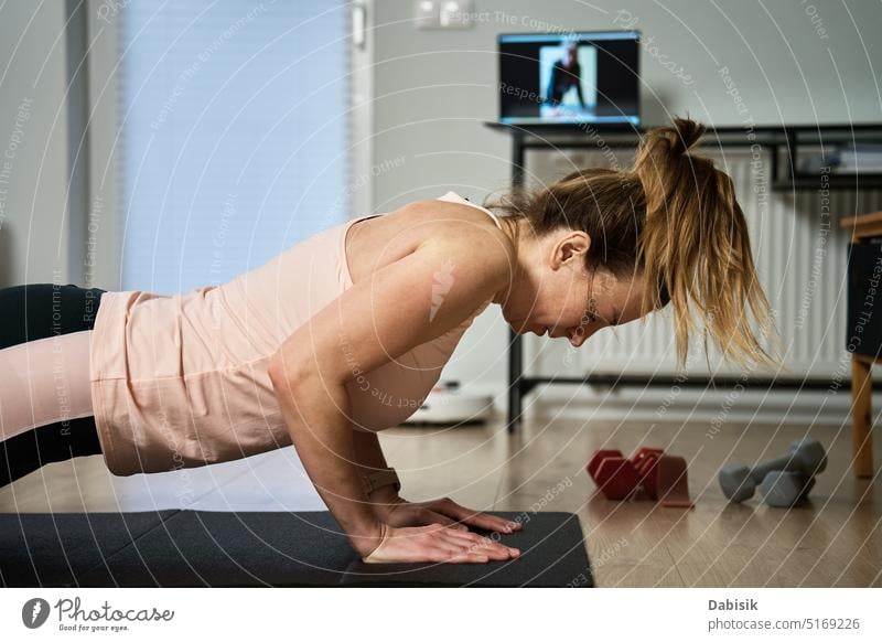 Frau in Sportkleidung macht Fitness- und Kardioübungen zu Hause, mit Laptop Training heimwärts Aktivität aktiv Körper Energie Übung gymnastisch Gesundheit