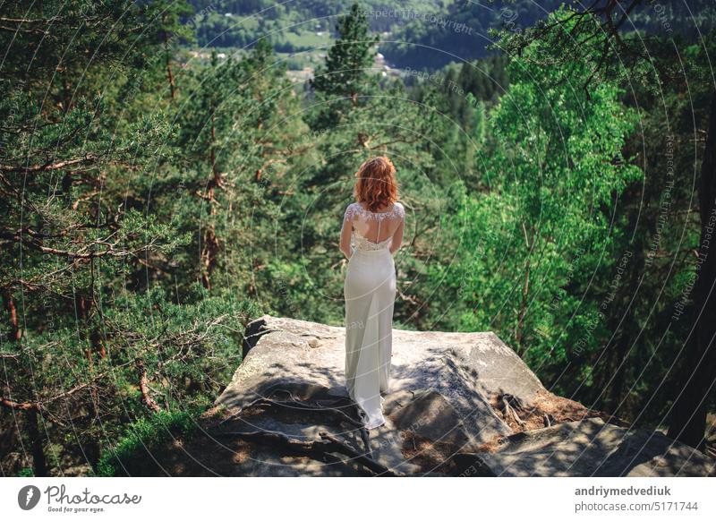 schöne junge rothaarige braut im wald mit einem blumenkranz auf dem kopf. frau im langen weißen kleid im freien an einem sommertag. hochzeitstag Braut Wälder