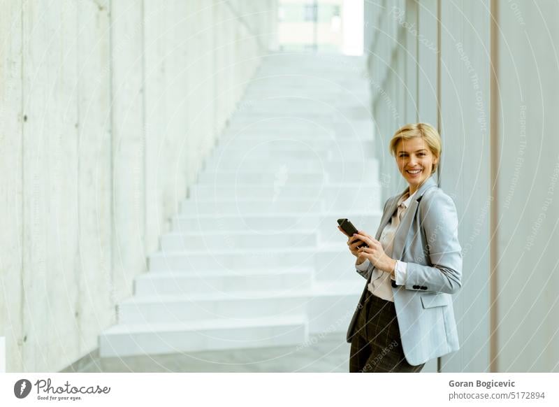 Geschäftsfrau benutzt Mobiltelefon in einem modernen Büroflur Erwachsener attraktiv Schönheit brünett Business Geschäftsperson Geschäftsleute Geschäftsmann