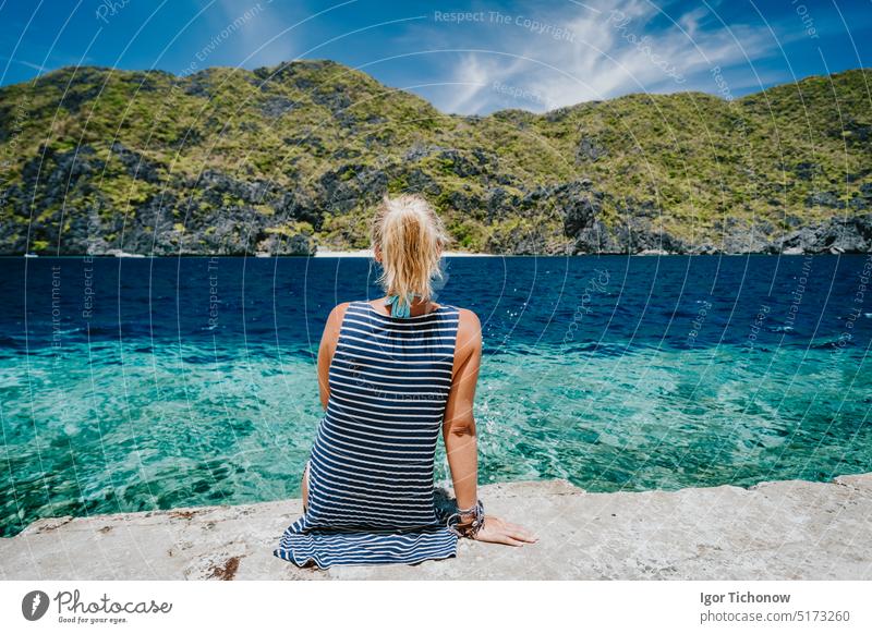 Tourist weiblich Rückansicht sitzen auf Matinloc Dock Pier genießen Tapiutan Straße auf Insel hoping Tour C. El Nido, Palawan, Philippinen Frau matinloc