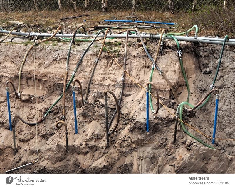 Sandige Baugrube mit vielen verschiedenen bunten Rohren und Schläuchen zur Entwässerung der Baustelle bauen Grube Schacht Handwerk Arbeit & Erwerbstätigkeit