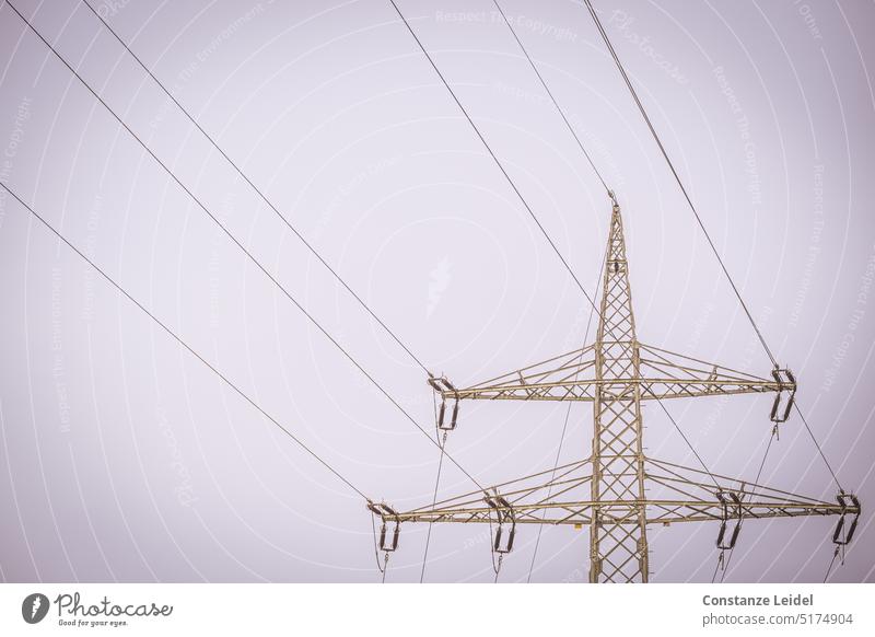 Hochspannungsmast goldfarben vor hellem Himmel. Strommasten Hochspannungsleitung Elektrizität Energiewirtschaft Industrie Stromtrasse Oberleitung Klimawandel