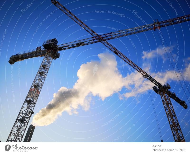 Baustelle mit rauchenden Kaminen und Kran vor blauem Himmel kräne Rauch drehkran Turmdrehkran Bauen werken Bauplan Arbeit Winter