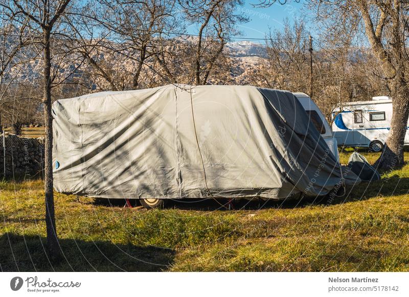 Ein mit einer Plane abgedeckter Wohnmobil-Wohnwagen Gurt Bauplane Campingplatz Kunststoff wasserdicht geparkt Pflege Dach Wetter Folie grau PKW Urlaub Wasser