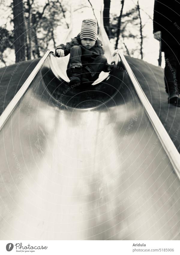 Kind rutscht sehr vorsichtig die sehr lange Rutsche runter in s/w Junge Spielplatz Spielen Außenaufnahme Kindheit rutschen Bewegung Mann Vater Papa Angst