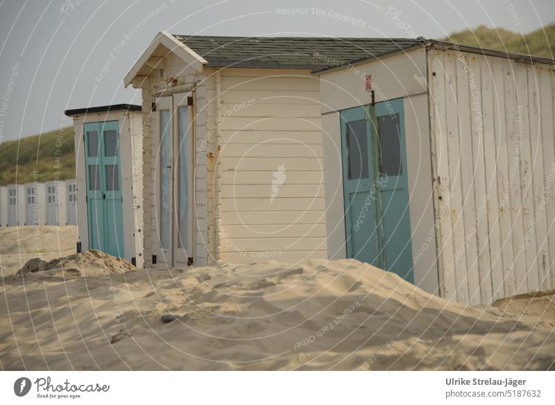 schiefe Strandhütten vom Sand umweht verweht cremfarben türkise Türen Holzhütten Hütten schiefe Hütten Hütten am Strand Ferien & Urlaub & Reisen Strandurlaub