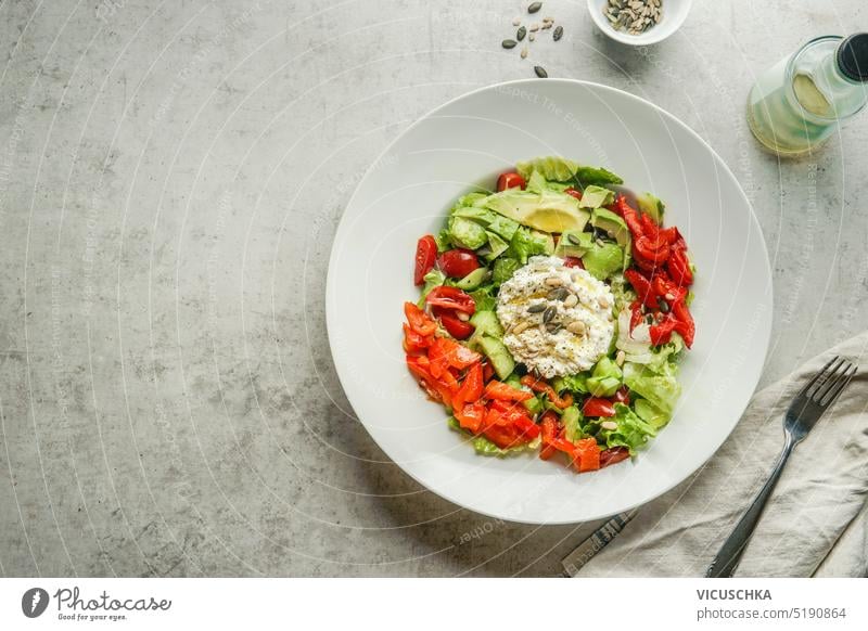 Leckeres Gemüse Salatschüssel mit frischem Käse, Nüsse und Samen auf dem Tisch mit Gabel, Draufsicht. Diät und gesunde Ernährung Konzept. geschmackvoll