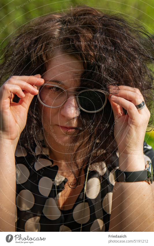 Porträt einer jungen Frau mit gespieltem strengen einäugigen Blick Frauenporträt schwarze haare Brille Gesicht Locken feminin Erwachsene Junge Frau Kopf schön