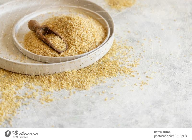 Haufen von trockenem, ungekochtem Bulgur-Weizenkorn mit einer Schaufel auf einem Teller, Nahaufnahme, Kopierraum. Gesundes Essen roh trocknen bulgur Korn