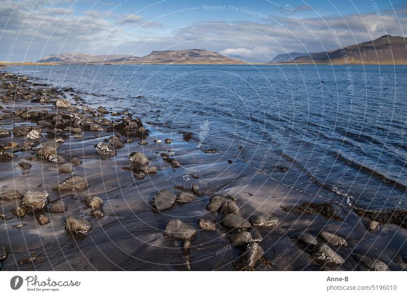 steiniger Sandstrand an einem skandinavischen Fjord, das Wasser ist auch im Sommer sehr kalt Skandinavien Strand blau Berge Wellen sanfte Wellen vegetationsarm