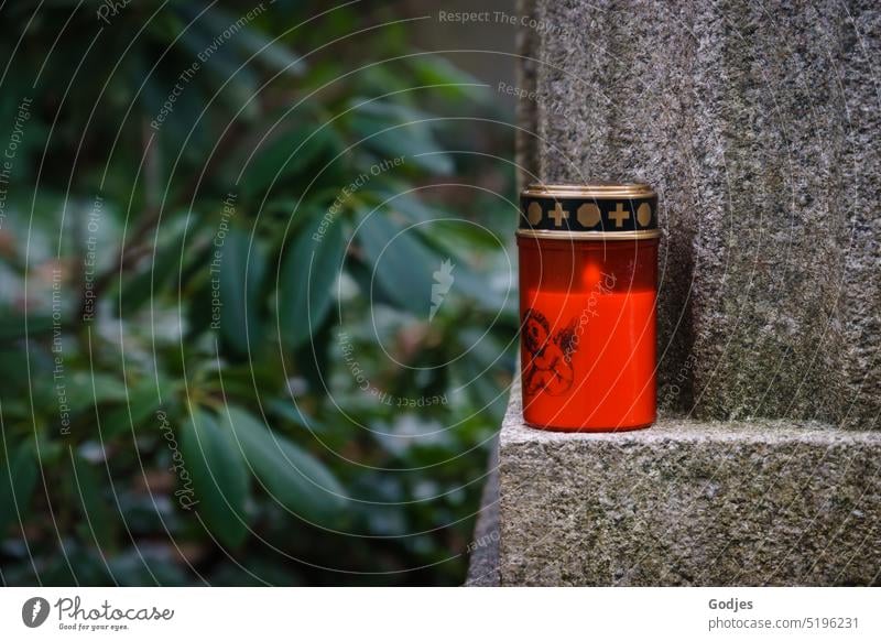 Rote brennende Grabkerze auf einem Grabstein vor grünem Hintergund grabkerze Vergehen Ohlsdorfer Friedhof Vergänglichkeit Trauer Außenaufnahme Farbfoto Tag