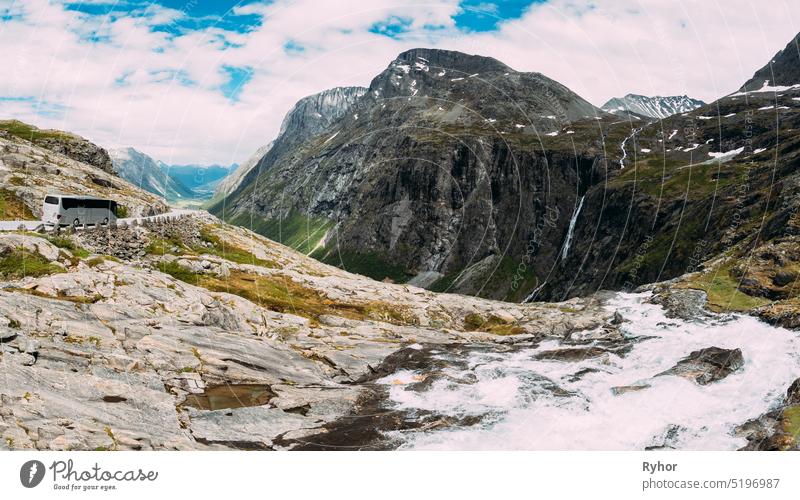 Trollstigen, Andalsnes, Norwegen. Bus fährt auf Straße in der Nähe von Stigfossen Wasserfall. Berühmte Bergstraße Trollstigen. Norwegisches Wahrzeichen und beliebtes Reiseziel. Norwegische Kreisstraße 63 an einem sonnigen Sommertag