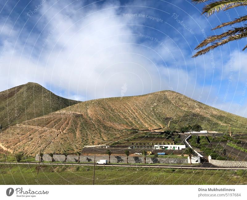 Schlafender Vulkan in Lanzarote, Spanien. Bauernhof in den Bergen am sonnigen Tag. Landschaft der Straße mit Blick auf die Berge und blauer Himmel.