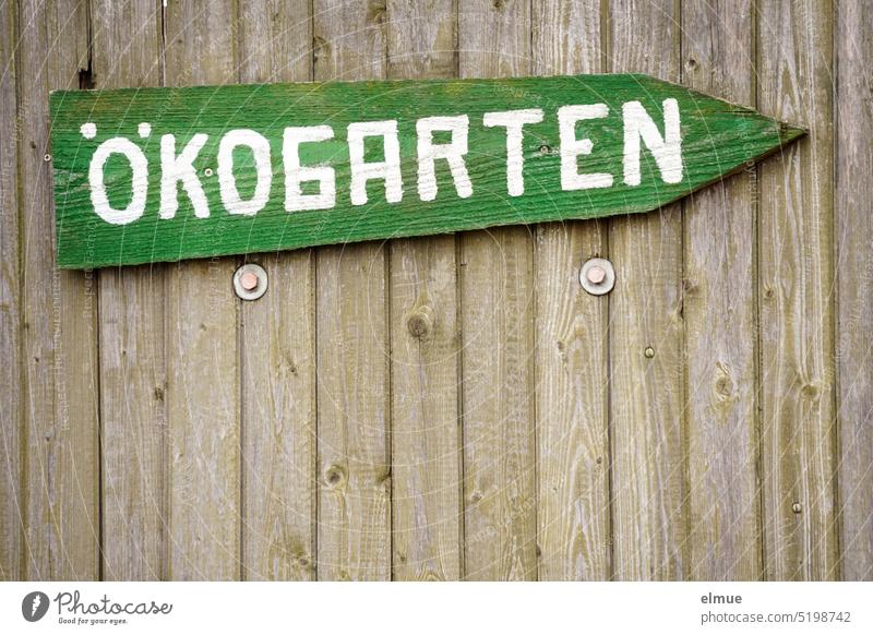 grünes Holzschild mit der Aufschrift ÖKOGARTEN an einem Holzlattenzaun Ökogarten Schild Holzzaun Zaun Hinweisschild Garten Pfeil Gartenzaun Ökoanbau nachhaltig