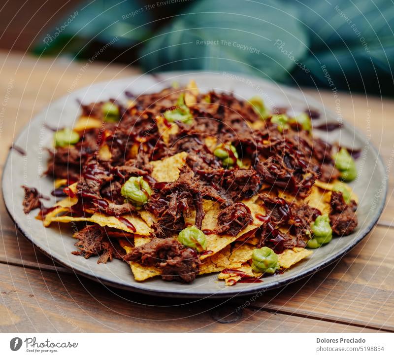 Mexikanische Nachos mit Rindfleisch und Chili auf Holztisch Amuse-Gueule sortiert Sortiment Avocado Hintergrund Bar Käse Peperoni Chili con Carne Chilischote