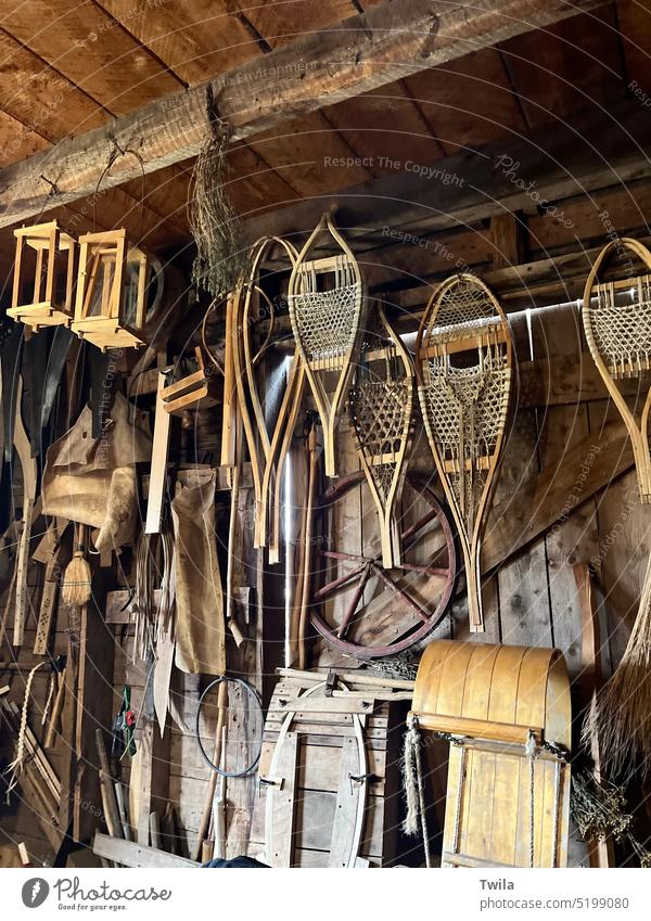 Werkstatt eines Bauernhofs aus dem Jahr 1800 mit Schneeschuhen, Schlitten und anderen Holzgegenständen historisch 1800's hölzern Toboggan Wagenrad altehrwürdig