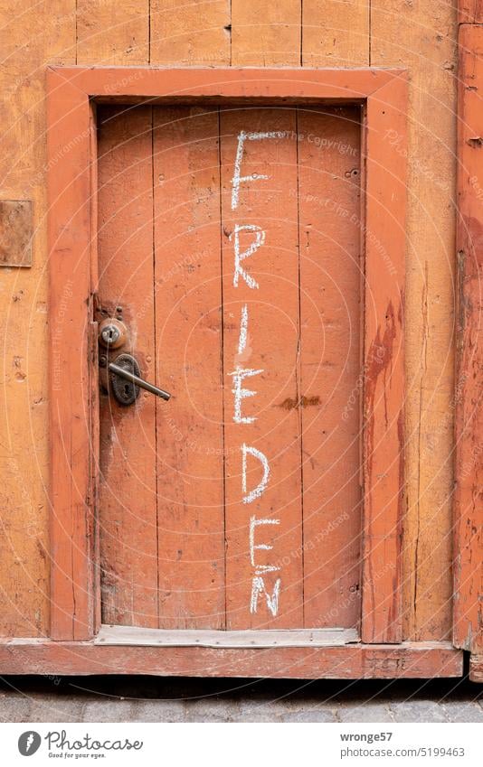 Frieden Großbuchstaben weiße Schrift Kreide Kreideschrift Tür Tor Holztür braun braune Tür braunes Tor alt Eingang Holztor Eingangstür geschlossen Menschenleer