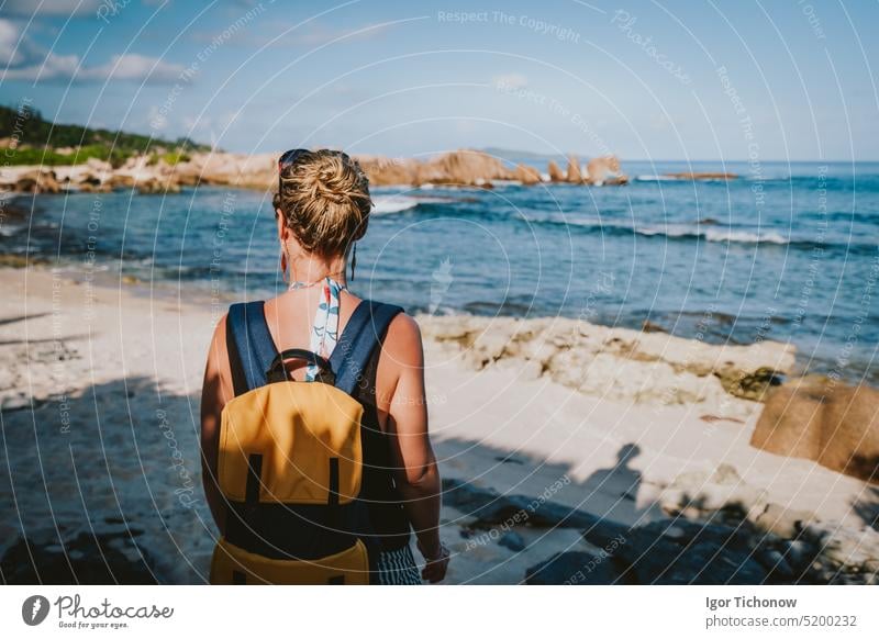 La Digue Insel, Seychellen. Erwachsene Frauen mit Rucksack genießen schönen tropischen abgelegenen Strand im Abendlicht Natur Hintergrund MEER Sand Felsen Meer