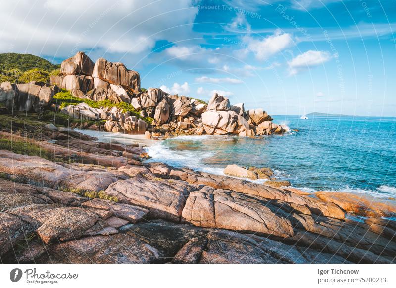 Abgelegener Strand Grand L Anse, La Digue, Seychellen. Tropische Meeresküste, einzigartige Granitfelsen und einsames Segelboot im Meer Feiertag Urlaub Sonne