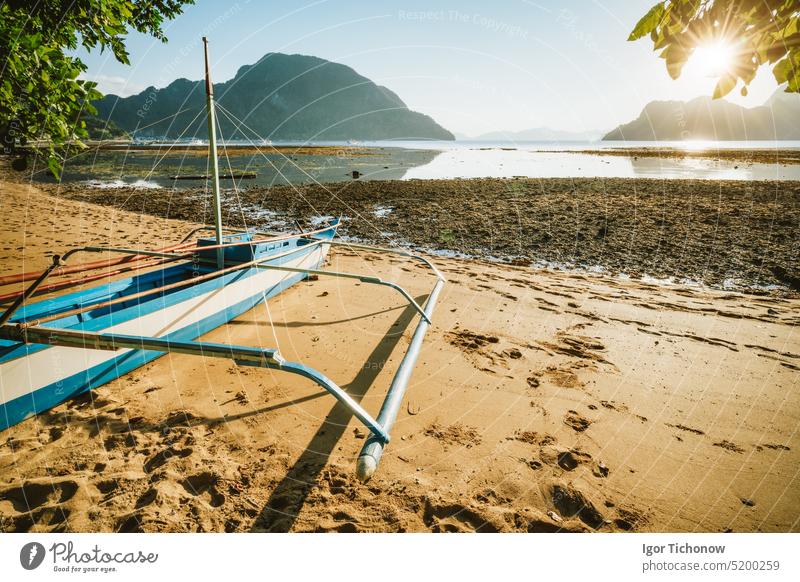 Bangka-Boot am Sandstrand mit goldenem Sonnenuntergangslicht über tropischen Inseln im Hintergrund. Bucht von El Nido. Philippinen schön Silhouette Natur reisen