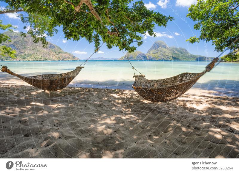 El Nido, Palawan, Philippinen. Bambus-Hängematten am Ufer im Schatten. Schöne tropische Lagune mit der epischen Insel Cadlao im Hintergrund reisen Urlaub