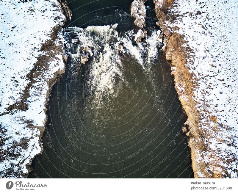 Wasserfall auf winterlichem Bach. Schnee auf gefrorenen Flussufern. Top Aerial View Of River Cascade. Stream Wasser fließt zwischen Felsen Winter Kaskade