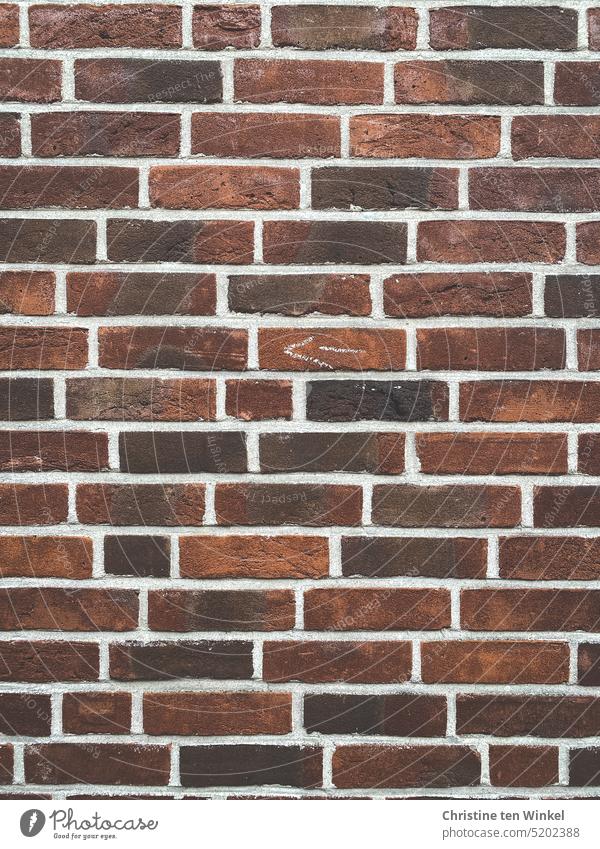 Eine alte Backsteinmauer mit einem kleinen gemalten Pfeil, der nach links zeigt Backsteinfassade Backsteinwand Pfeilsymbol Wand Mauer Fassade Backsteine rot