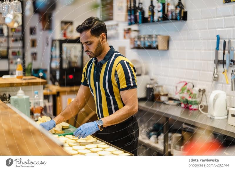 Junger Mann bereitet frische Lebensmittel in einer Großküche zu Beruf Besitzer jung Person Mitarbeiter professionell Job indischer Mann asiatisch Catering