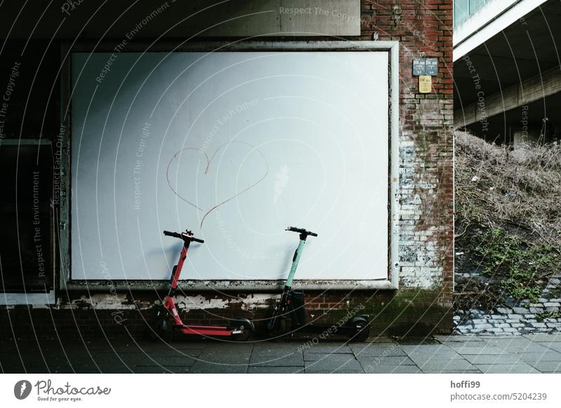 zwei E-Roller  vor weisser Plakatwand mit rotem Herz weiße wand Mobilität elektrisch Verkehrsmittel modern Straße Lifestyle Scooter Elektroroller E-Scooter