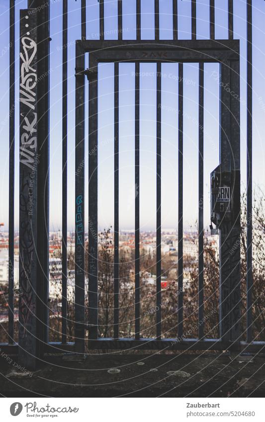 Tür in einem Gitter, dahinter Blick auf die Stadt Tor Eingang Ausgang Sperre versperrt öffnen schließen Chancen Aussicht verschlossen ausweglos hoffnungslos