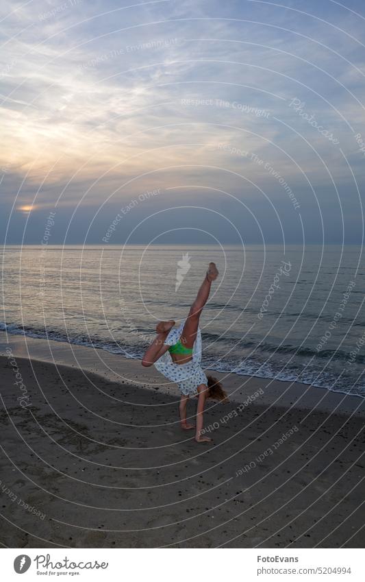 Mädchen im Kleid macht einen Handstand am Strand vor dem Meer bei Sonnenuntergang Kind Sand Sandstrand Natur Landschaft Sport Aktiv Spaß Freude Fun Glücklich