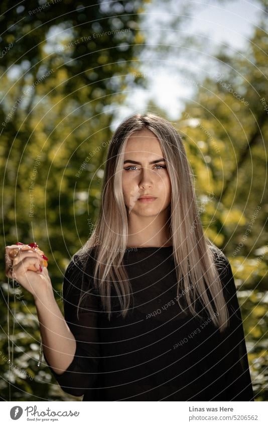 Die schöne Blondine nimmt die Sache ernst. Sie hat gerade ein Ei in ihrer Hand zerschlagen und schaut dabei direkt in die Kamera. Schwarzes Outfit. Rote Nägel. Ein hübsches Gesicht, das nicht ganz so unschuldig ist.