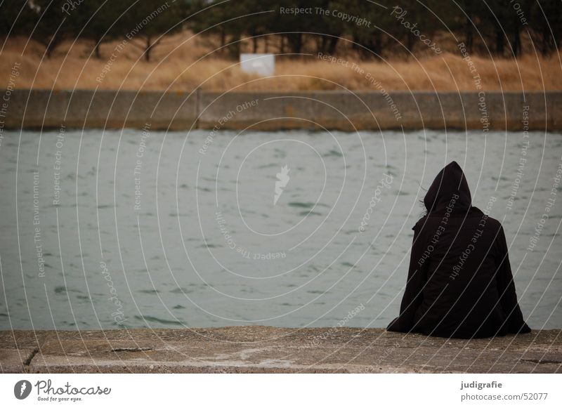 Dunkle Gestalt an der Mole Meer Winter Mensch 1 Natur Wasser Ostsee Hafen Jacke Kapuze Beton sitzen warten dunkel kalt schwarz Darß Farbfoto Gedeckte Farben