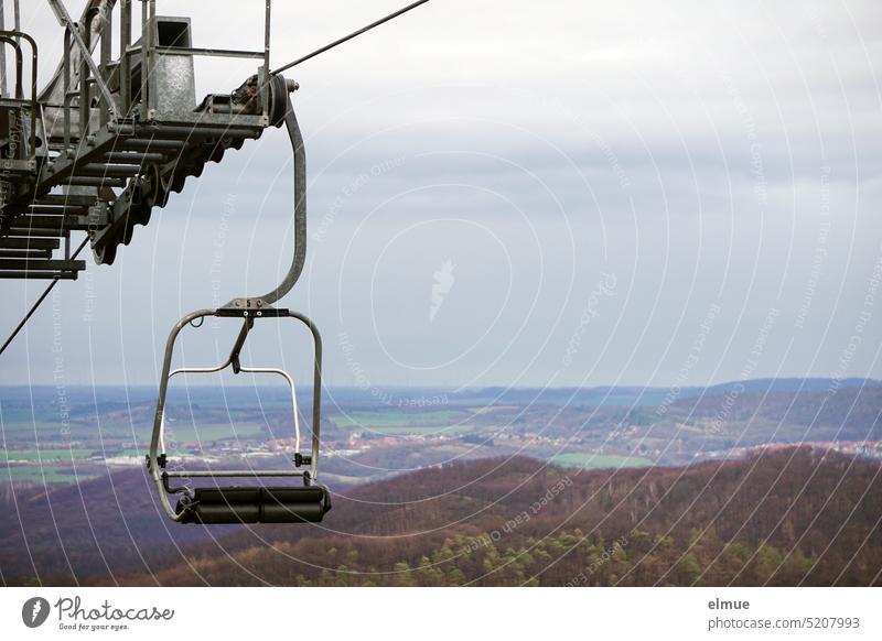 Sesselbahn mit leerem 2er Sessel und Ausblick auf schneefreies Hügelland Sessellift Seilbahn Wintersportgebiet Umlaufseilbahn Sicherheitsbügel Aussicht Blog