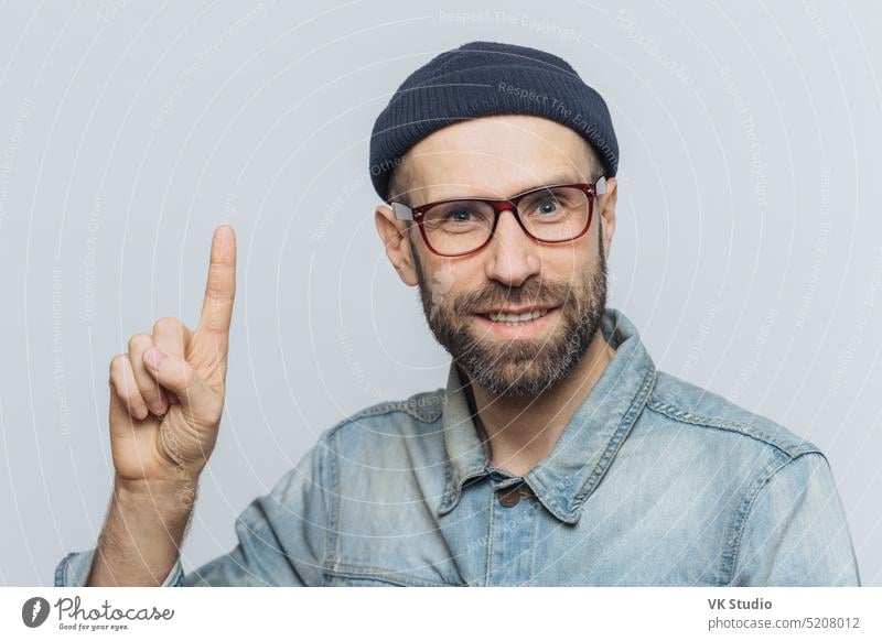 Menschen, Emotionen und Reaktion Konzept. Handsome bärtigen Mann in trendigen Brillen, hat zufriedenen Ausdruck, hebt vorderen Finger als erinnert sich an etwas Positives, isoliert über graue Studio Hintergrund