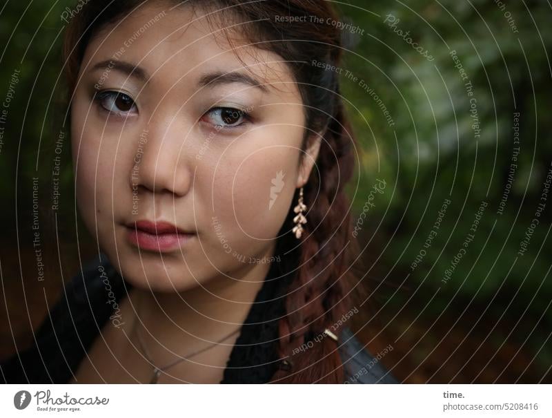 Frau mit Ohrschmuck weiblich feminin Schmuck Blick zur Seite Wald Portrait langhaarig dunkelhaarig Zopf Flechtzopf nachdenklich