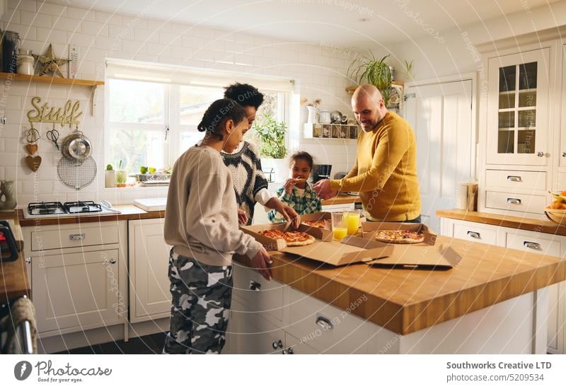 Familie mit einem Jungen mit Down-Syndrom genießt Pizza zum Mitnehmen zum Abendessen Takeout heimwärts Imbissbude rassenübergreifend Mahlzeit Lebensmittel