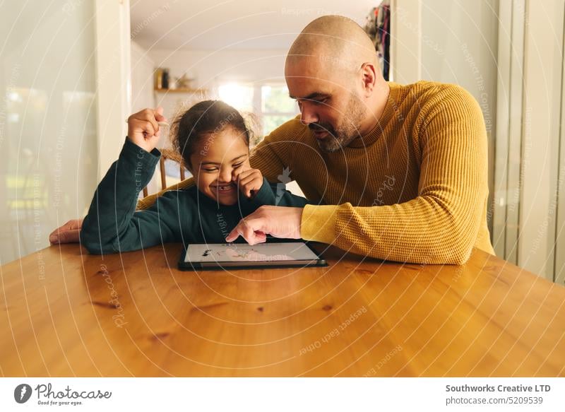 Mehrrassiger Vater und Sohn mit Down-Syndrom nutzen digitales Tablet für Hausaufgaben Vatertag digitales Tablett Lifestyle rassenübergreifend Mann Junge Kind