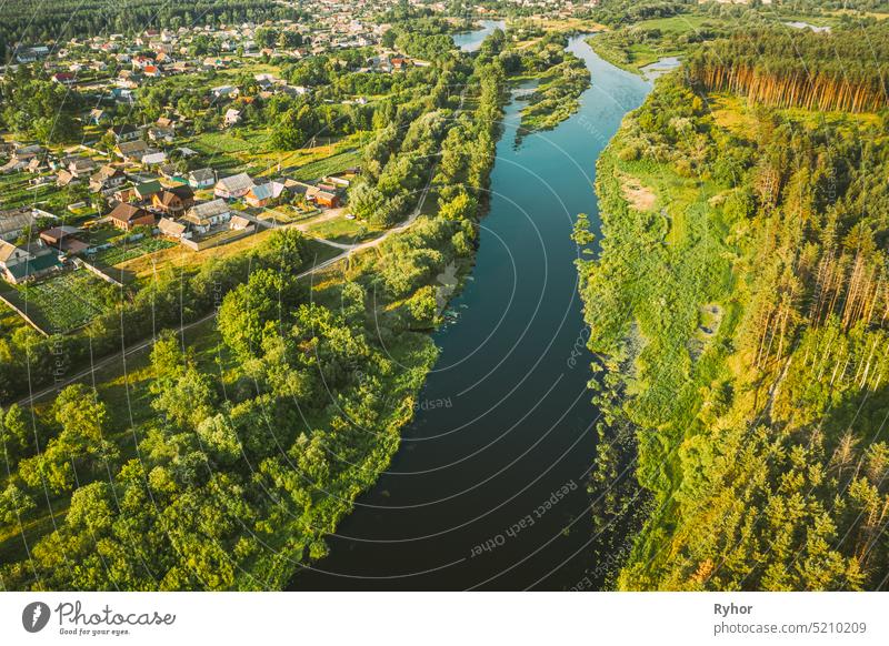 Luftaufnahme von ruhigen Fluss und Dorf in Belarus, Europa. Green Forest Woods Landschaft in sonnigen Sommerabend. Top View of Beautiful European Nature From High Attitude. Drone Ansicht. Vogelperspektive Ansicht