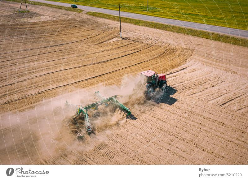 Luftaufnahme. Traktor pflügt Feld. Beginn der landwirtschaftlichen Frühjahrssaison. Cultivator Pulled By A Tractor In Countryside Rural Field Landscape. Staub steigt von unter Pflügen