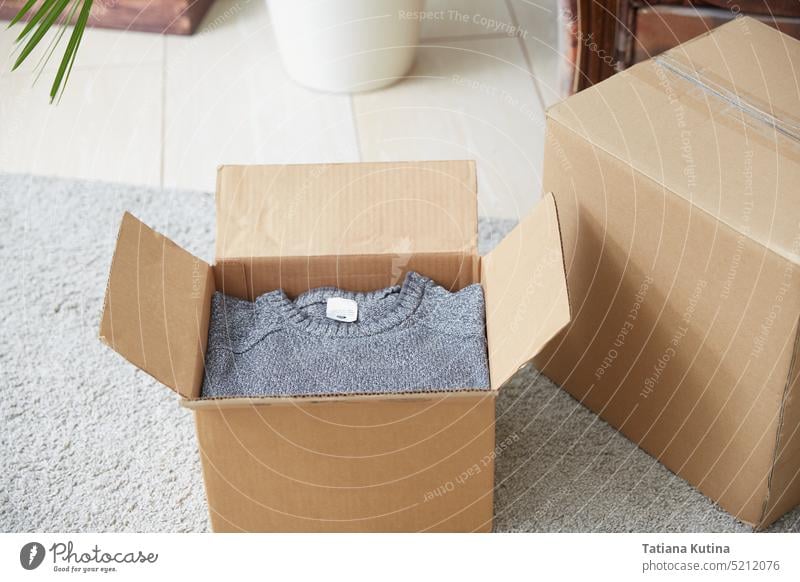 Eine Kiste mit Dingen auf dem Teppich im Zimmer. Das Konzept des Umzugs oder der Auslieferung. Kasten Verpackung Karton Paket Lager Raum lebend Nahaufnahme