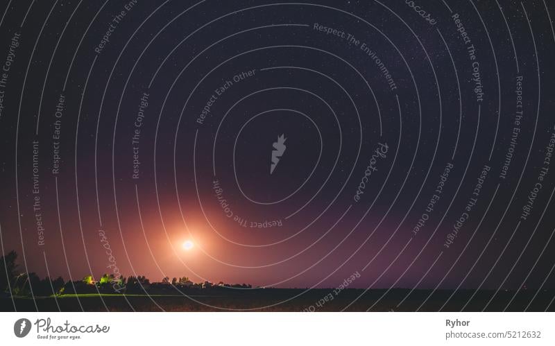 Mondaufgang über weißrussischen Dorf in Osteuropa. Weißrussische Landschaft im Sommer sternenklarer Nacht Himmelshintergrund kosmisch Stern Glühende Sterne