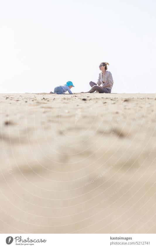 Mutter spielt sein Kleinkind Junge Sohn auf Sandstrand genießen Sommerferien auf der Insel Lanzarote, Spanien. Familie Reisen und Urlaub Konzept. Ferien