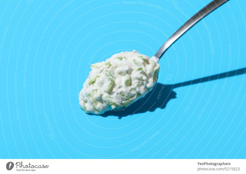 Tzatziki-Sauce auf einem Löffel, isoliert auf blauem Hintergrund oben Amuse-Gueule Frühstück hell cacik Nahaufnahme Farbe Textfreiraum Sahne Salatgurke Küche