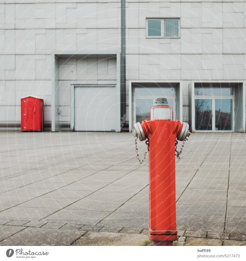 Hydrant und rote mobile Toilette vor grauer Wand Hydrat mobile Toiletten Toilettenhäuschen notdurft Notdurft Öffentliche Toilette Mobile WC weiß Klo sanitär wc