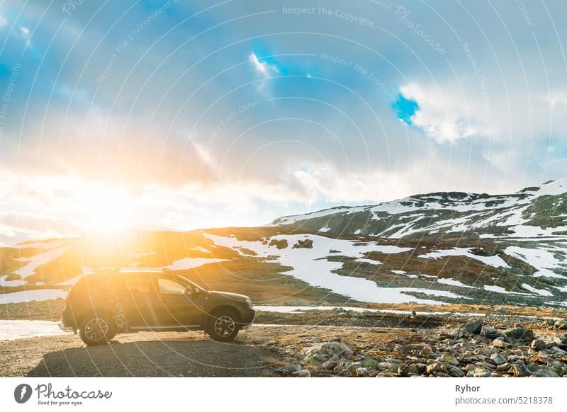 Aurlandsfjellet, Norwegen. Auto SUV geparkt in der Nähe Aurlandsfjellet Scenic Route Straße im Sommer norwegischen Landschaft. Beliebtes Reiseziel in Sonnenuntergang Lichter. Sonnenschein