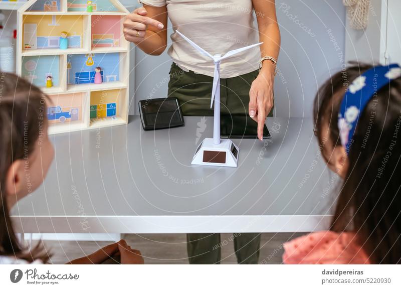 Lehrerin zeigt ihren Schülern im Ökologieunterricht eine Windmühle unkenntlich Frau solar regenerativ Energie Kinder Klassenraum Schule Bildung zeigend