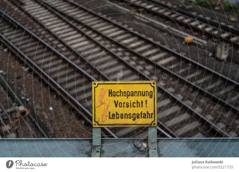 Warnung vor Hochspannung an den Gleisen Farbfoto Tag Außenaufnahme Schrift Stadt Menschenleer Schriftzeichen Zeichen Strom Gefahr gefährlich Warnschild Achtung